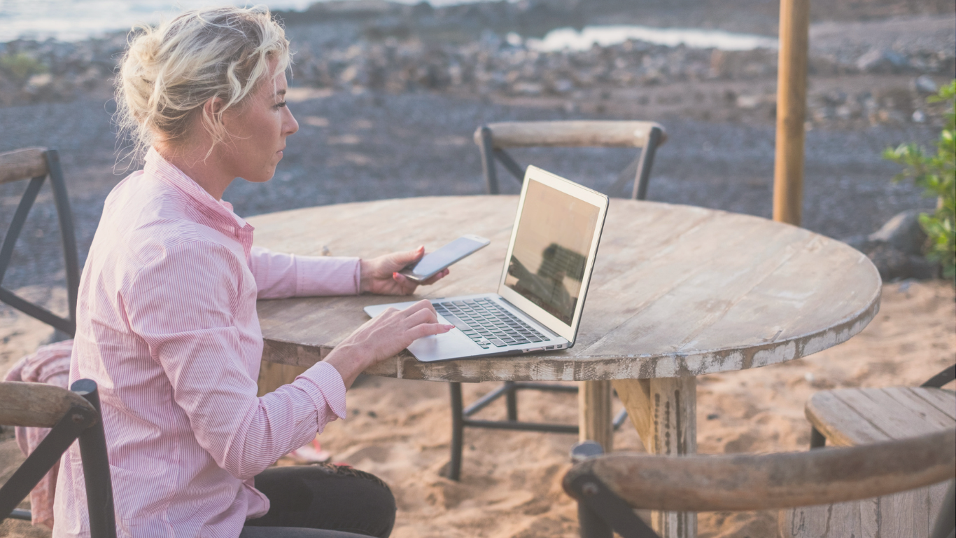 A digital nomad relaxing with a laptop at a camper van campsite, representing flexible work and van life travel.